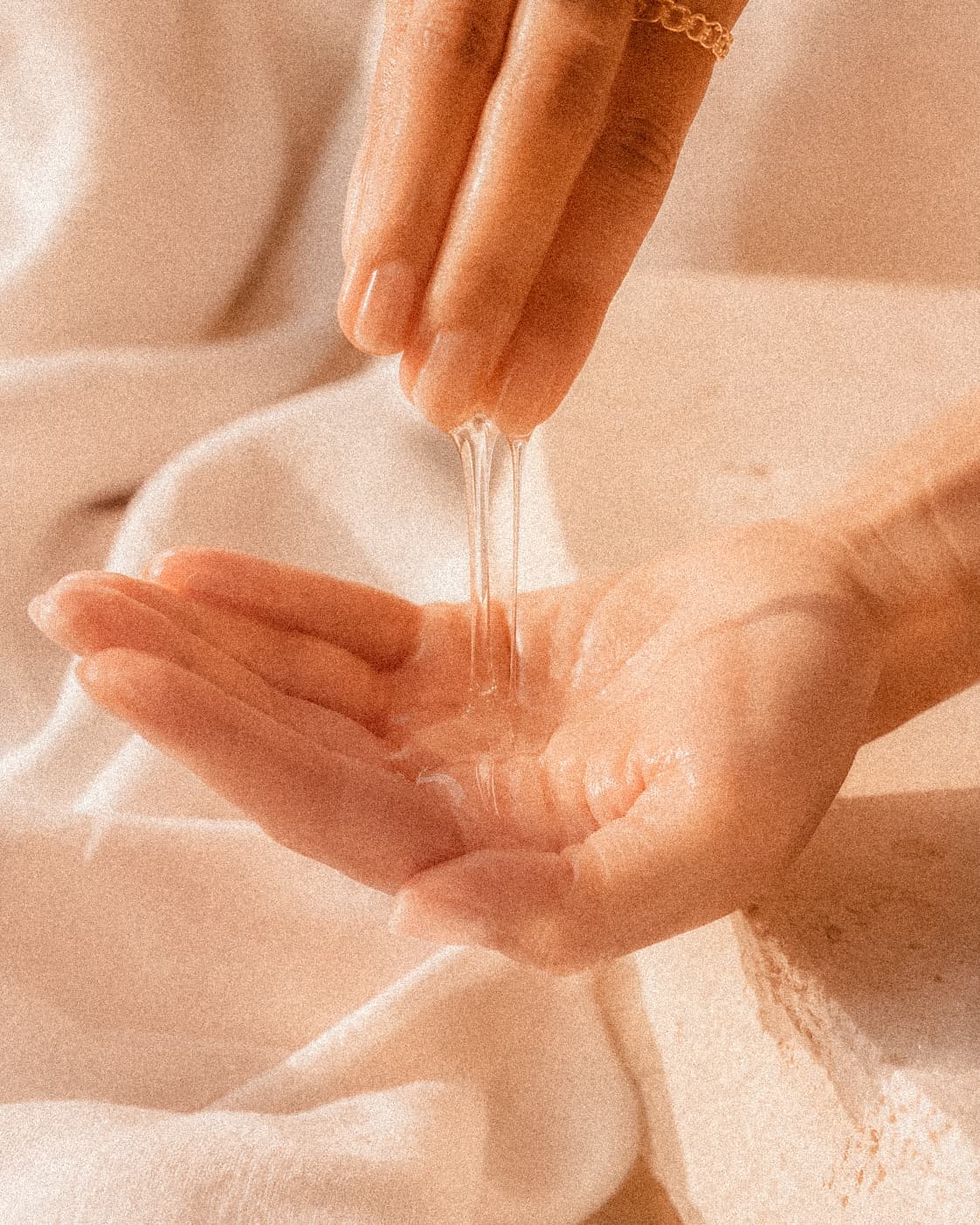 A hand letting Khaea Mineral Texture Serum drip slowly across an open palm in warm afternoon light